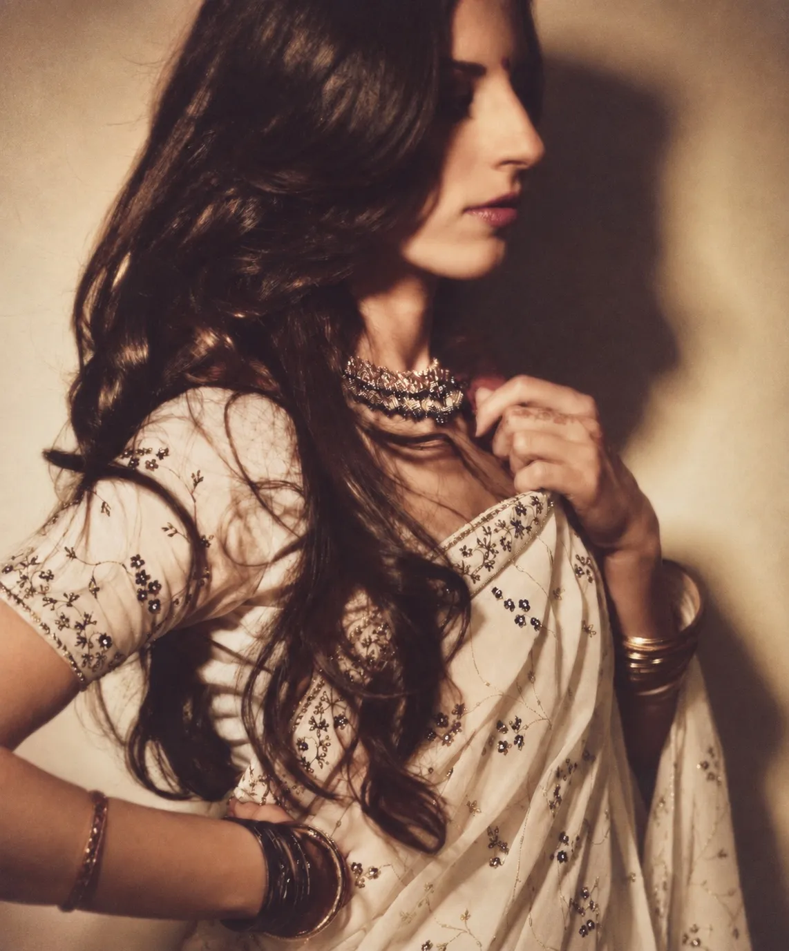 Dalia Lane in a white embroidered sari, looking away over her shoulder